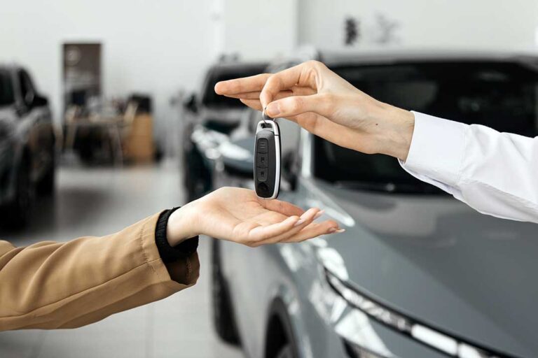 A person comparing options while looking at used and new cars in a dealership lot.