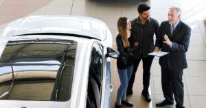 Buyer reviews a vehicle inspection report beside a clean certified pre-owned vehicle.